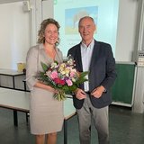 Person mit Blumenstrauß steht neben einer anderen Person 