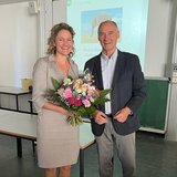 Person mit Blumenstrauß steht neben einer anderen Person 