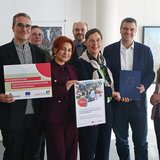 Gruppenbild mit acht Personen, zwei von ihnen haben ein Poster in der Hand.